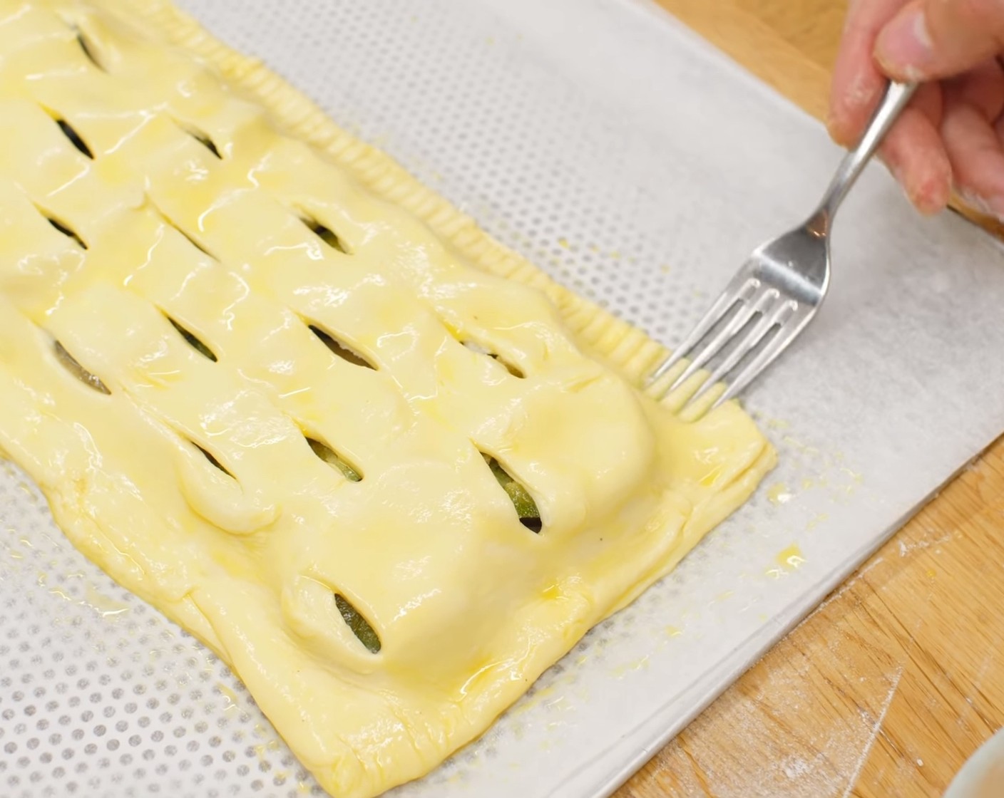 Schritt 18 Dieses geschnittene Teigstück auf die Zwetschgen legen. Die beiden Teigstücke an den Kanten schön bündig verbinden und etwas andrücken. Zum Schluss den ganzen Strudel mit dem verquirlten Ei bestreichen und die Kanten mit einer Gabel leicht markieren bzw. andrücken (wie bei Ravioli).