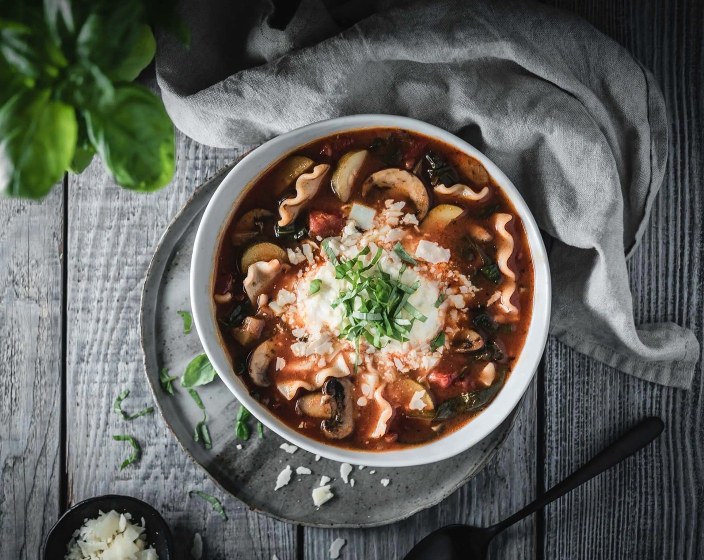 Schritt 6 Die Suppe in Schüsseln füllen. Mit Mozzarella (455 g), Ricotta (455 g) und Parmesan (wenig) darüber verteilen. Zum Schluss mit Basilikum (wenig) garnieren und warm servieren.