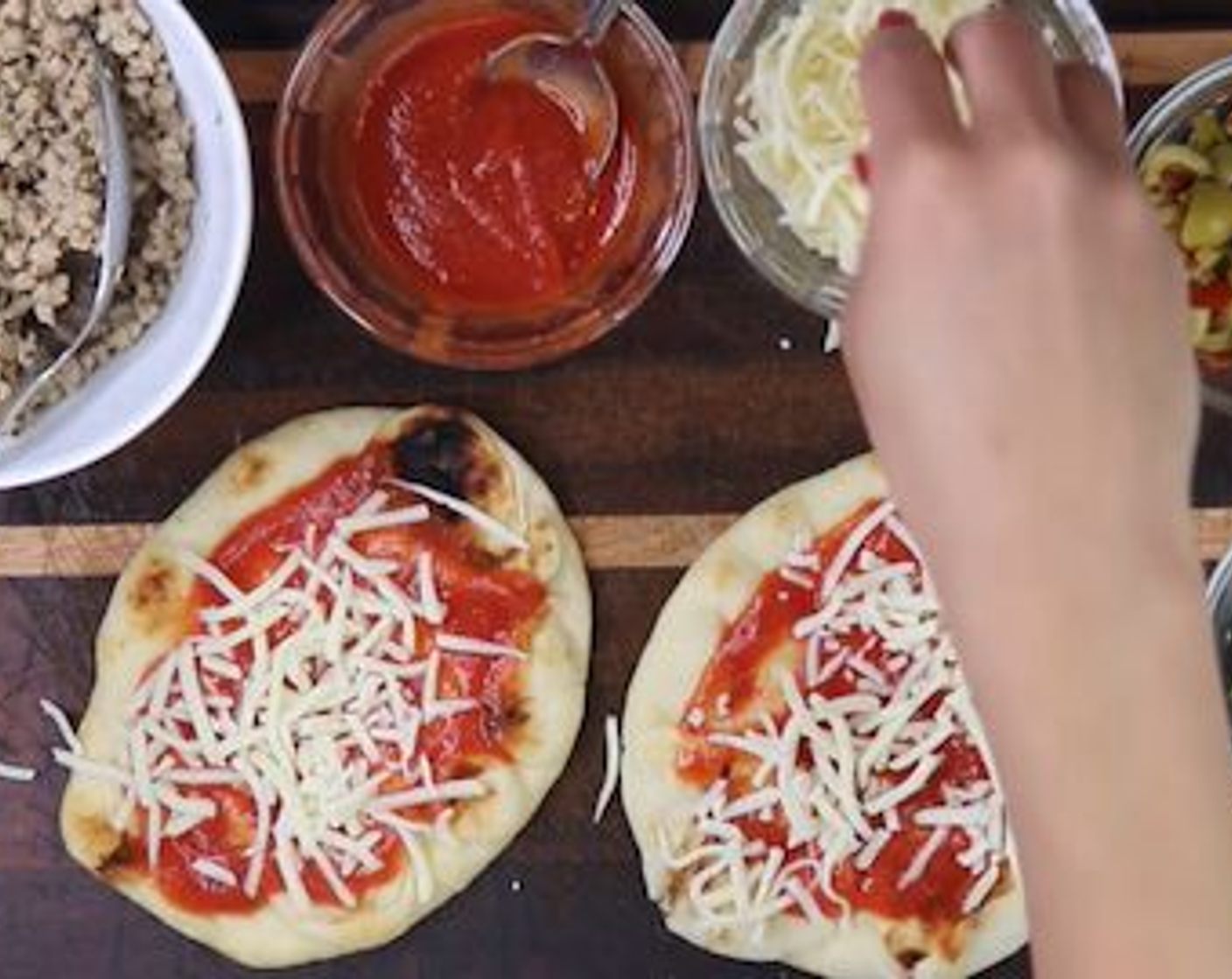 Schritt 5 Naan-Brote (4) auf eine flache Unterlage legen. Gewünschten Belag vorbereiten. 
Jetzt die Naan "Pizza" zusammensetzen: Tomatensauce (wenig) darauf verteilen, gefolgt von der Hälfte der gewünschten Menge Mozzarella (wenig). Mit Schweinefleisch belegen und dann noch etwas Mozzarella darauf streuen.