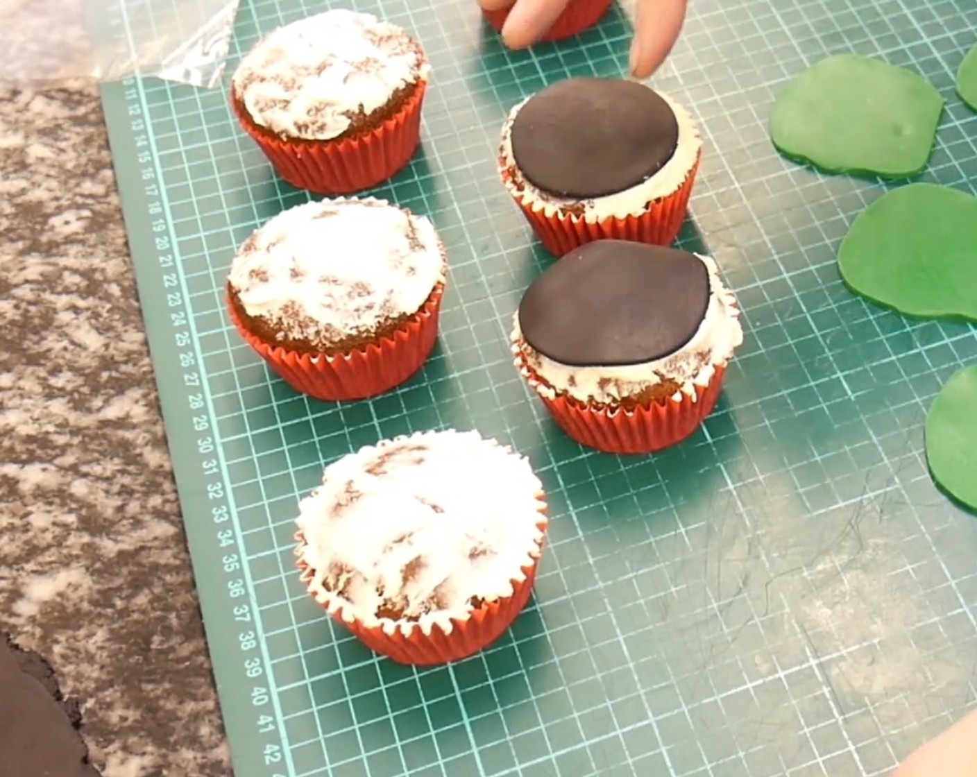 Schritt 9 Die vorbereiteten und ausgekühlten Cupcakes mit etwas Buttercreme bestreichen und die schwarzen Rollfondant Kreise darauf legen.